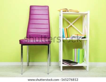 Beautiful interior with modern  color chair,  books on wooden stand, on wall background