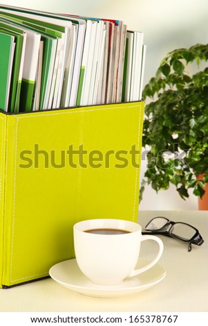 Magazines and folders in green box,on office interior background