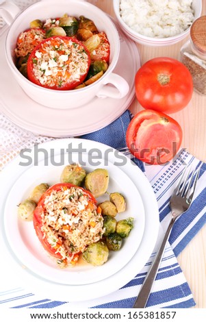 Stuffed tomatoes in plate and pan on wooden table close-up