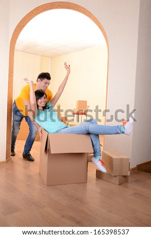 Young couple fooling around in new house on room background