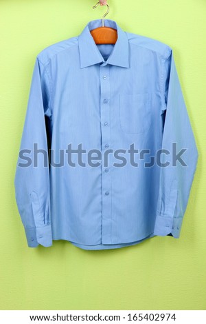 Male shirt on hanger on wall background