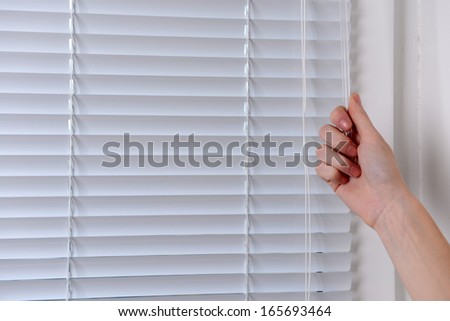 Hand opening window with white jalousie, close up