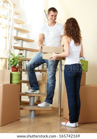 Young couple with boxes in new home on staircase