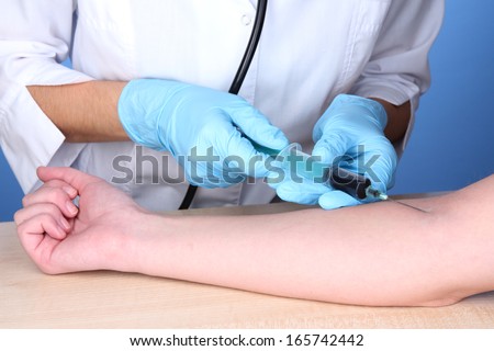 Nurse takes blood from the veins on blue background