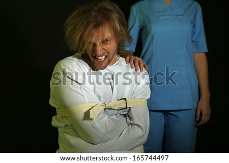 Mentally ill man in strait-jacket on black background