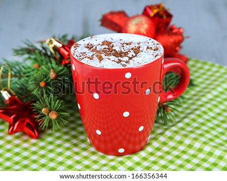 Hot chocolate with cream in color mug, on napkin, on Christmas decorations background