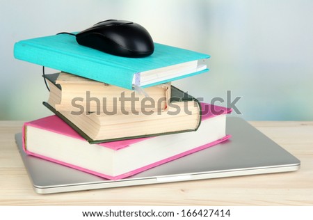 Computer mouse on books and notebook on wooden table on room background