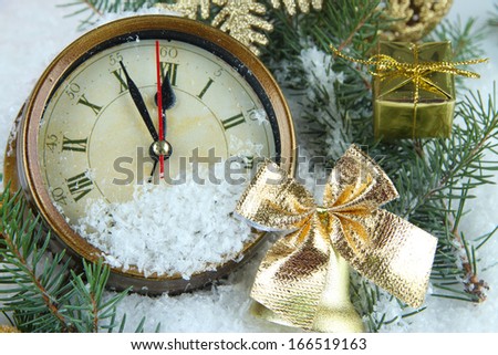 Clock with fir branches and Christmas decorations under snow close up