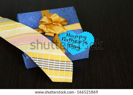 Happy Fathers Day tag with gift boxes and tie, on wooden background