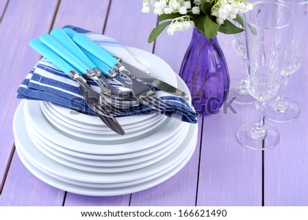 Clean dishes on wooden table on color background