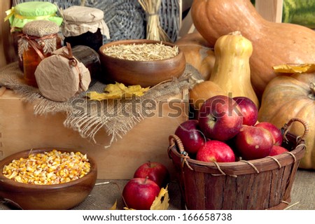 Fruits and vegetables with jars of jam and bowls of grains on sackcloth on wooden background
