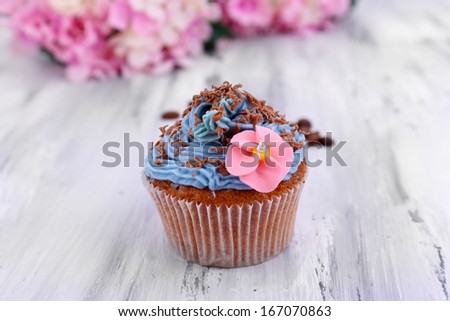 Tasty cupcake with butter cream, on color wooden background