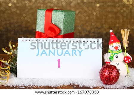 Calendar, New Year decor and fir tree on shiny golden background