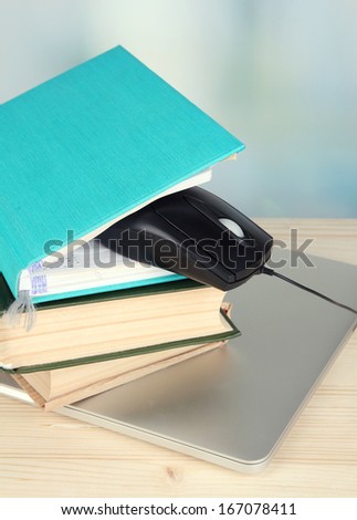 Computer mouse on books and notebook on wooden table on room background
