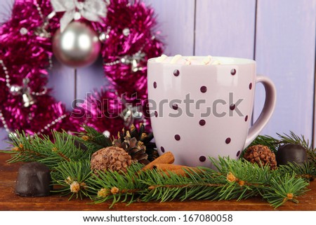 Cup of hot cacao with chocolates and fir branches on table on wooden background