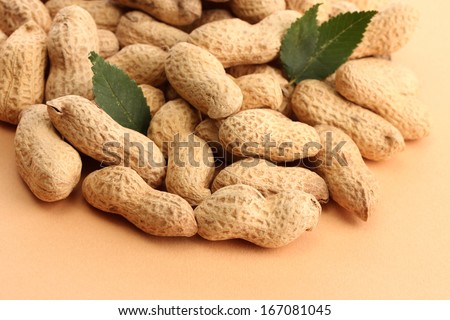 tasty peanuts with green leaves, on beige background