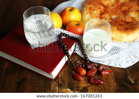Composition with traditional Ramadan food, holy book and rosary, on wooden background