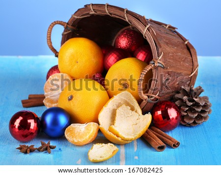 Christmas tangerines and Christmas toys in basket on blue background