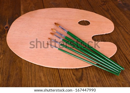 Wooden art palette and brushes on table close-up