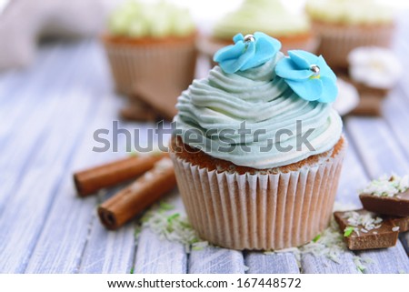 Tasty cupcakes with butter cream, on color wooden background