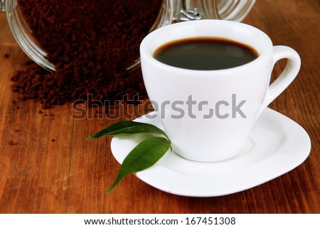 Cup of coffee with scattered instant coffee isolated on white