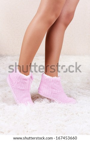 Female legs in home winter shoes, on white carpet background