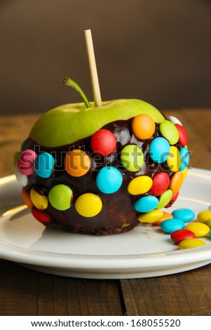 Candied apple on stick on wooden table