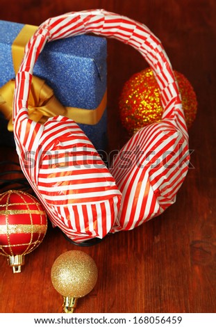 Headphones packed in gift paper with gifts on wooden table close-up