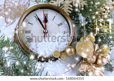 Clock with fir branches and Christmas decorations under snow close up