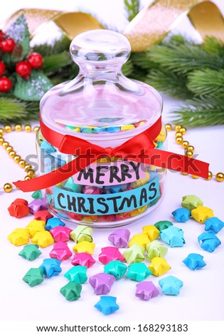 Paper stars with dreams in jar on white background