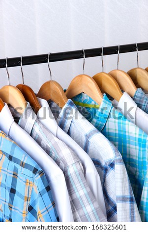 Men\'s shirts on hangers on light background