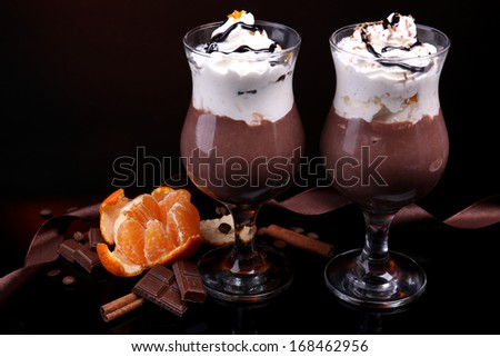 Tasty dessert with chocolate, cream and orange sauce, on dark color background