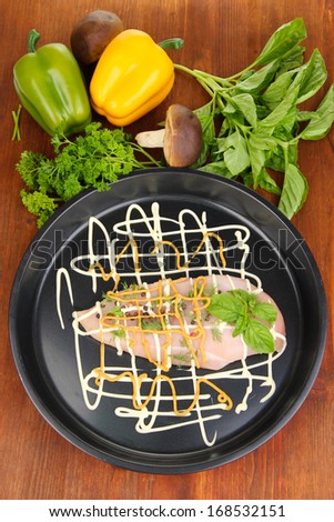 Raw chicken fillets on dripping pan, on wooden background