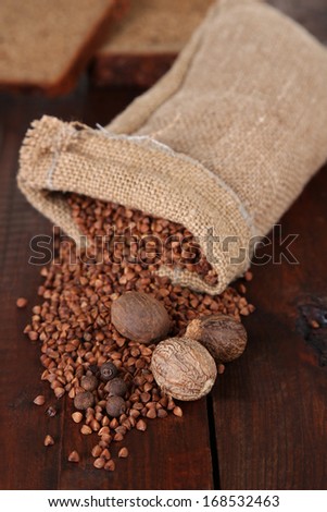 Cloth bag with buckwheat groats and spices on wooden background