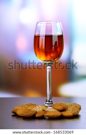 Glass of amaretto liquor and roasted almonds, on bright background