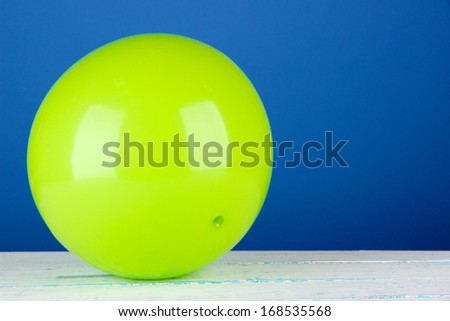 Bright green ball on table on blue background