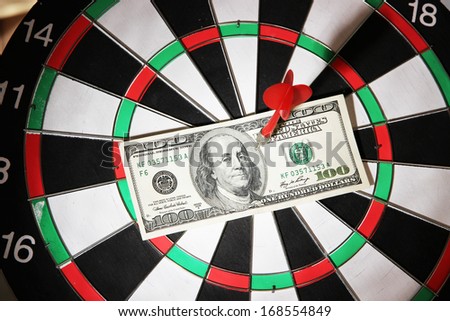 Money pierced by arrow on dartboard close up