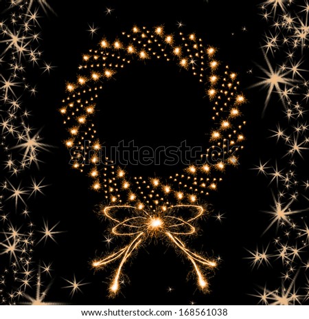 Christmas sparklers in shape of Christmas wreath on black background