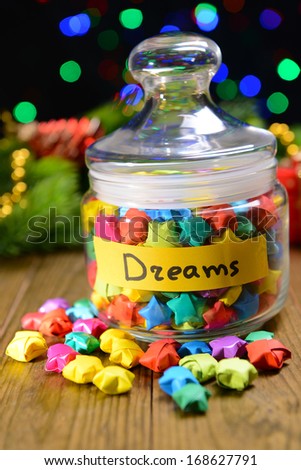 Paper stars with dreams on table on dark background