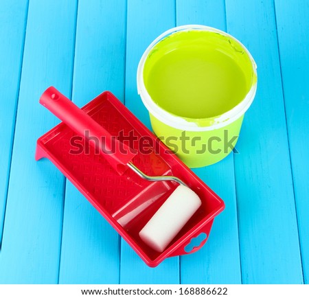 Set for painting: paint pot, paint-roller on blue wooden table