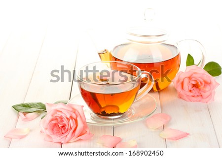 teapot and cup of tea with roses on white wooden table