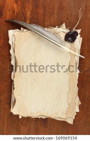 Old paper and feather on wooden background