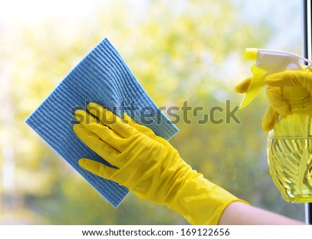 Hands with spray cleaning the window