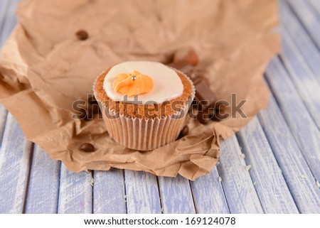 Tasty cupcake with butter cream, on color wooden table, on wooden background
