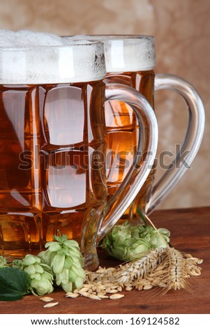 Glasses of beer and hops, on wooden table