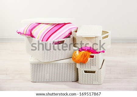 Plastic baskets with things in floor on room background