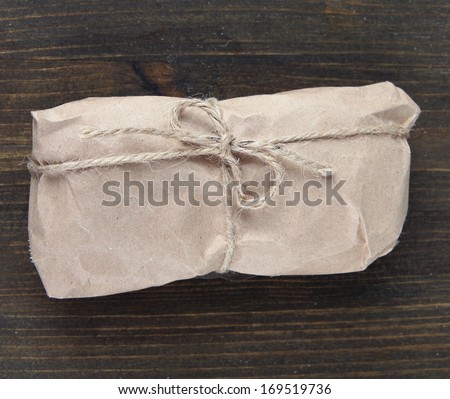 Telephone wrapped in brown kraft paper, on wooden background