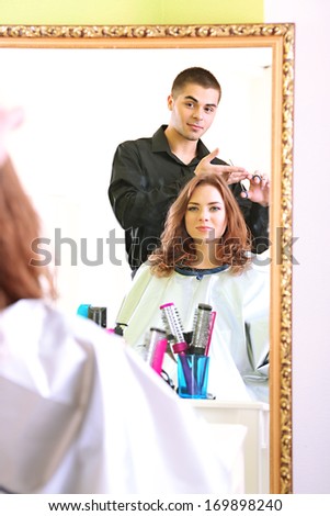 Young man hairdresser makes hairstyle girl in beauty salon