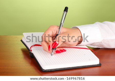 Hand signing in notebook  on wooden table on color background