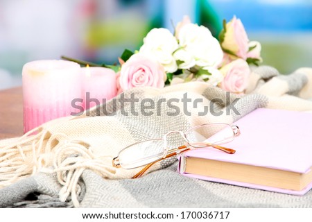 Composition with old book, eye glasses, candles, flowers and plaid on bright background